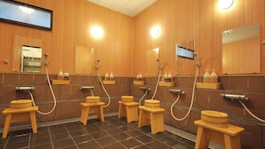 Des toilettes publiques avec des murs en bois, plusieurs lavabos et des tabourets en bois.