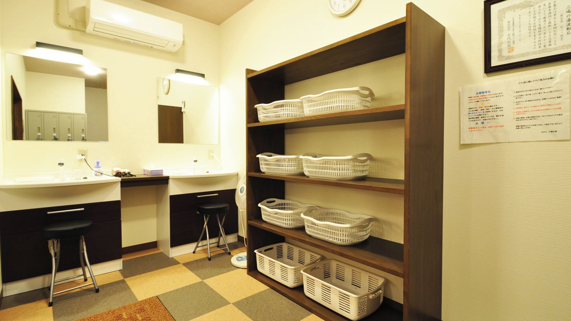 A hotel bathroom with a sink, mirror, and shelves with baskets.