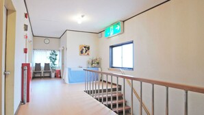 Un couloir avec un escalier, un comptoir d’accueil et une horloge au mur.