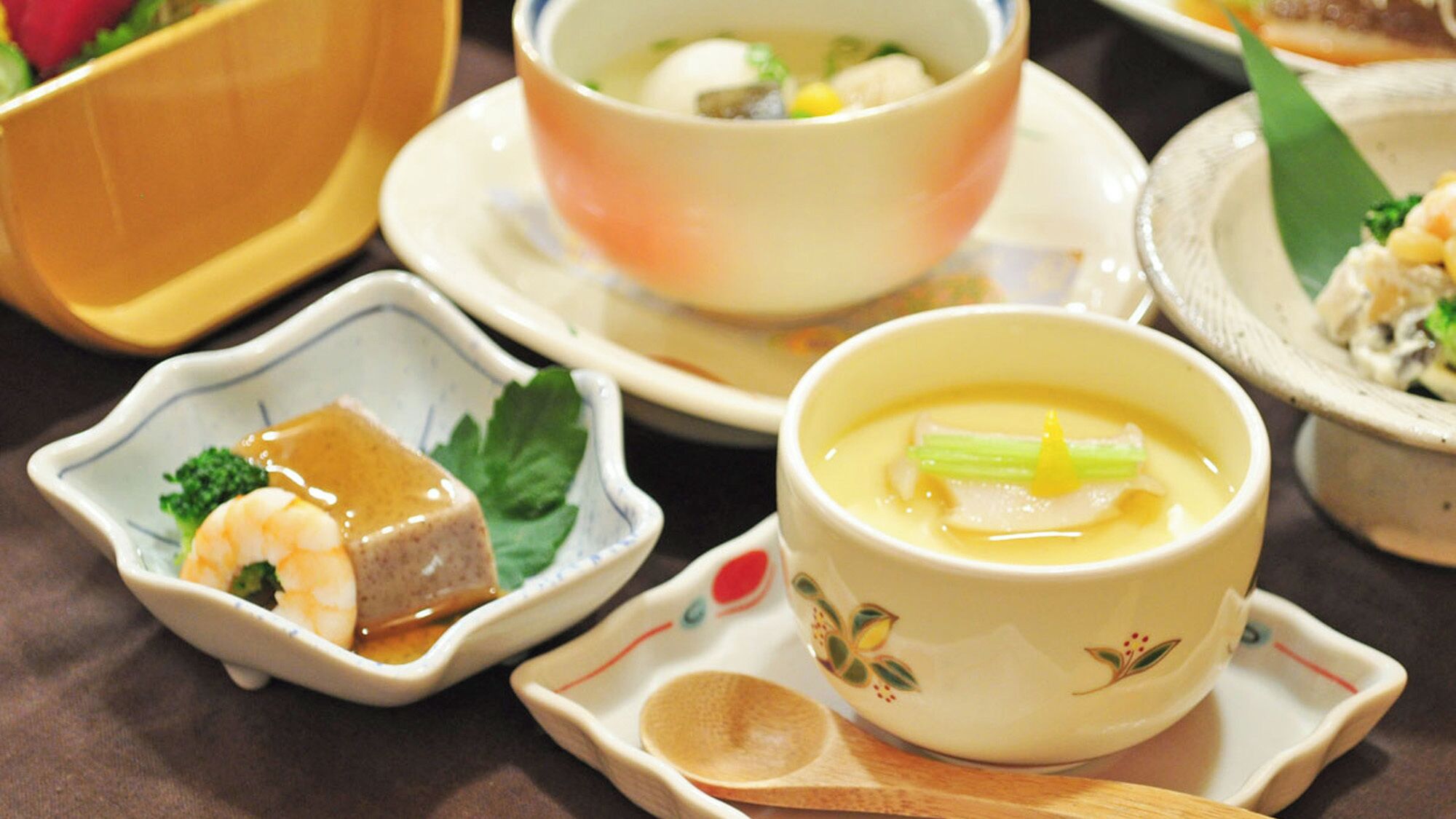 On vous proposera un assortiment de plats, notamment une soupe, un plat aux crevettes et un plat avec une sauce jaune.