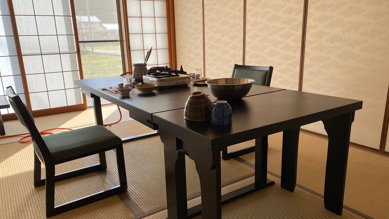 Une pièce de style japonais traditionnel, avec un sol recouvert de tatamis, une petite table sur laquelle sont posés un bol et une théière, ainsi qu’une chaise.