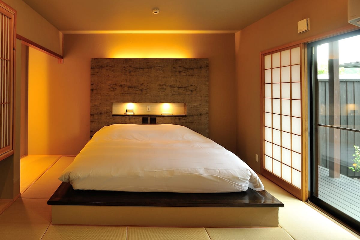 Um quarto com uma cama, um armário de madeira e uma porta de correr.