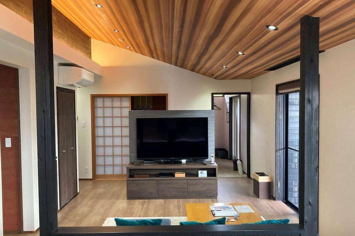 Sala de estar moderna com televisão de tela plana sobre um console de madeira, uma porta deslizante e vista para o exterior.
