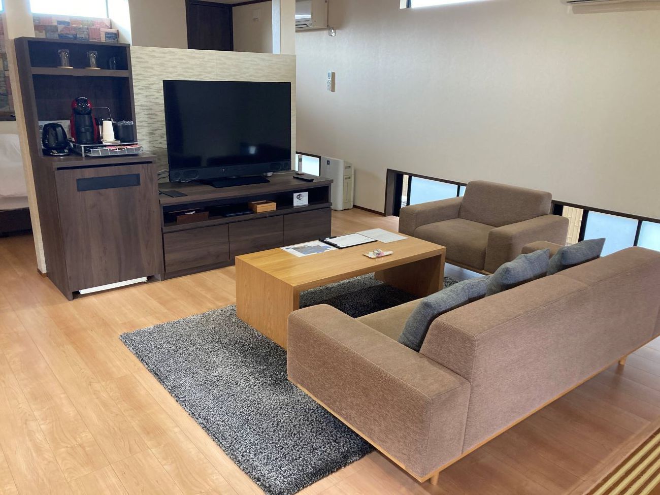 Een woonkamer met een bank, salontafel, televisie en een houten kast.