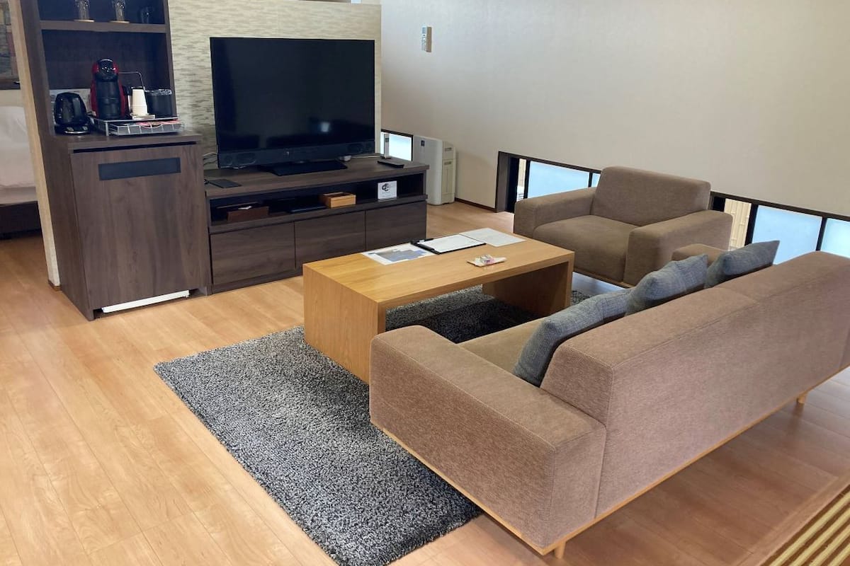 Uma sala de estar com sofá, mesa de centro, televisão e um armário de madeira.