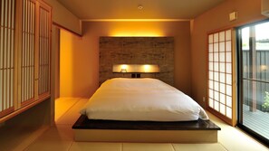 Una stanza con un letto, un armadietto in legno e una porta scorrevole.