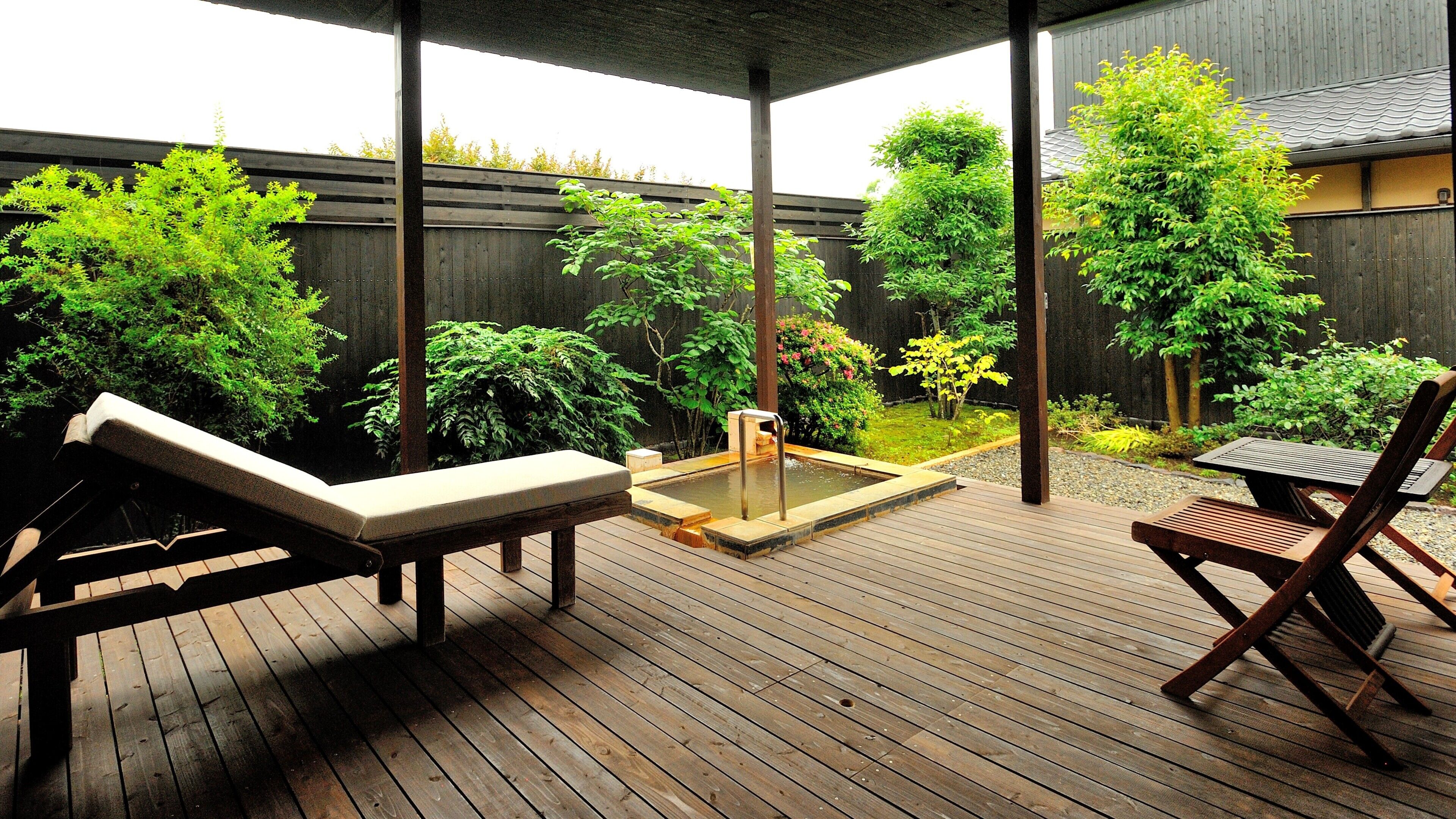 A wooden deck with two lounge chairs and a hot tub.