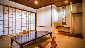 Una habitación japonesa tradicional con suelo de tatami, una mesa baja, puertas correderas y una obra de caligrafía en la pared.