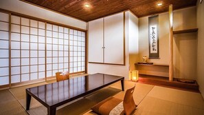 Um quarto japonês tradicional com tatames, uma mesa baixa, portas deslizantes e uma obra de caligrafia na parede.