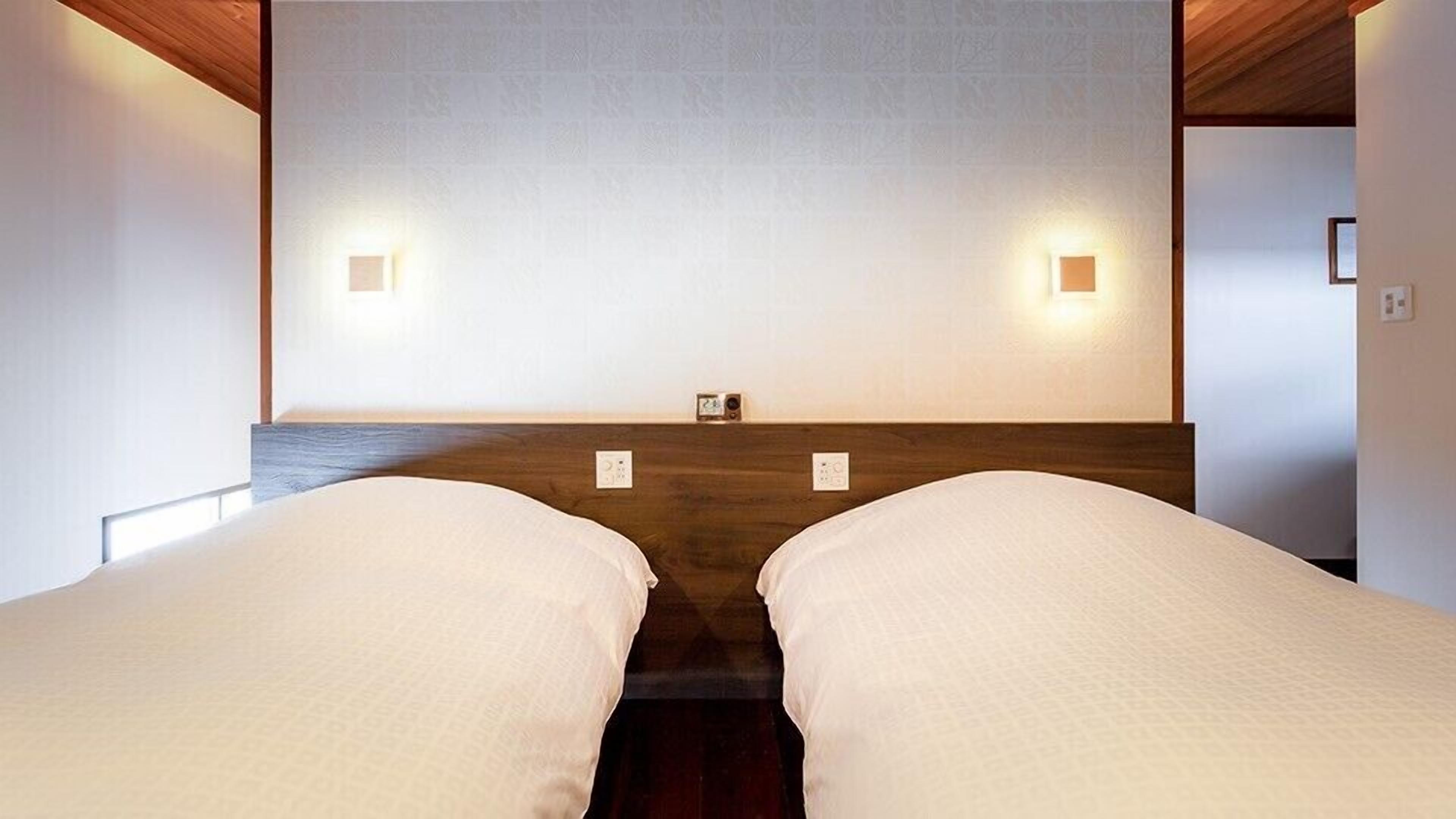 Ein Zimmer mit zwei Betten, einem hölzernen Kopfteil und Wandleuchten.