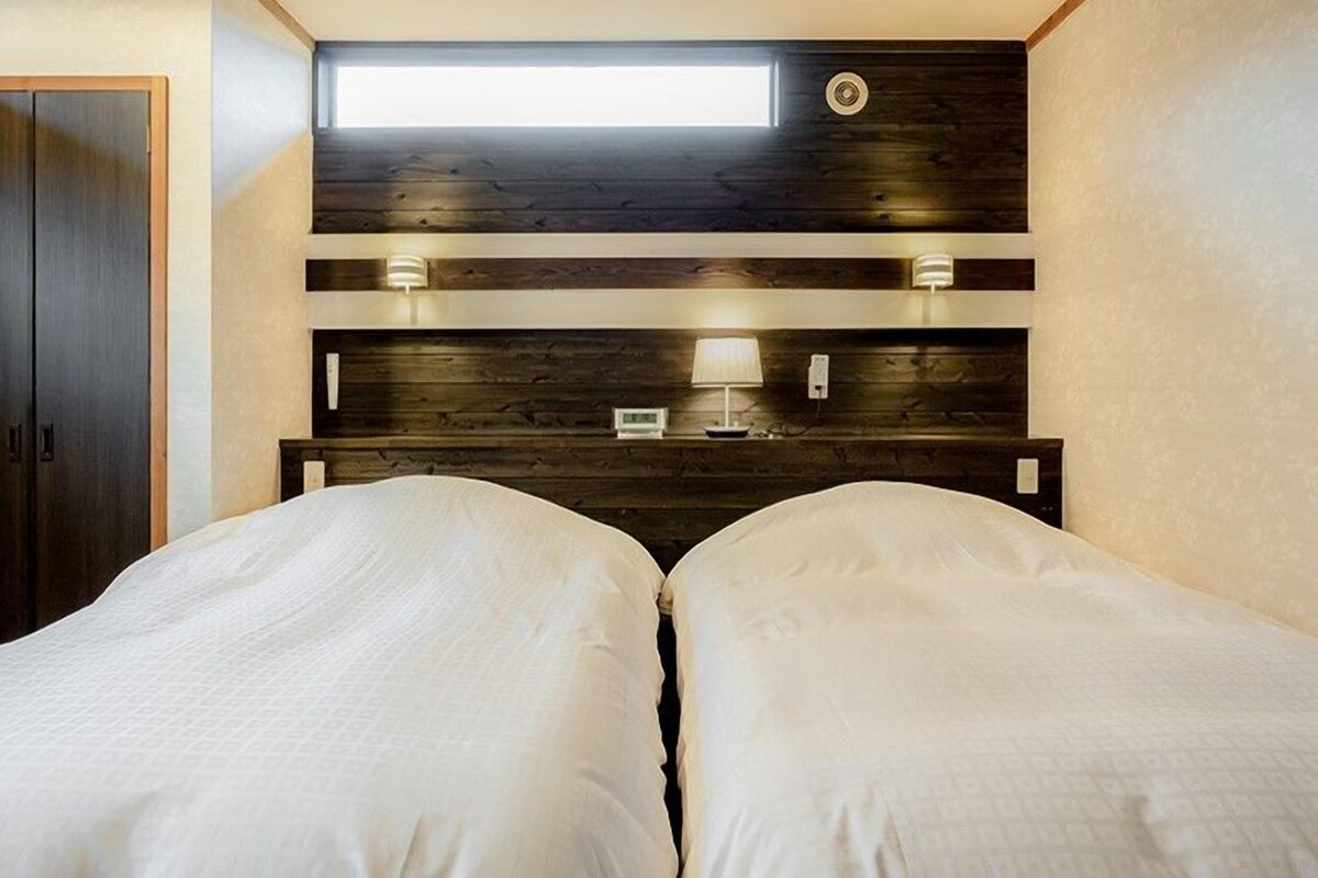 Una camera da letto con due letti, un lucernario, una testiera in legno e lampade ai comodini.