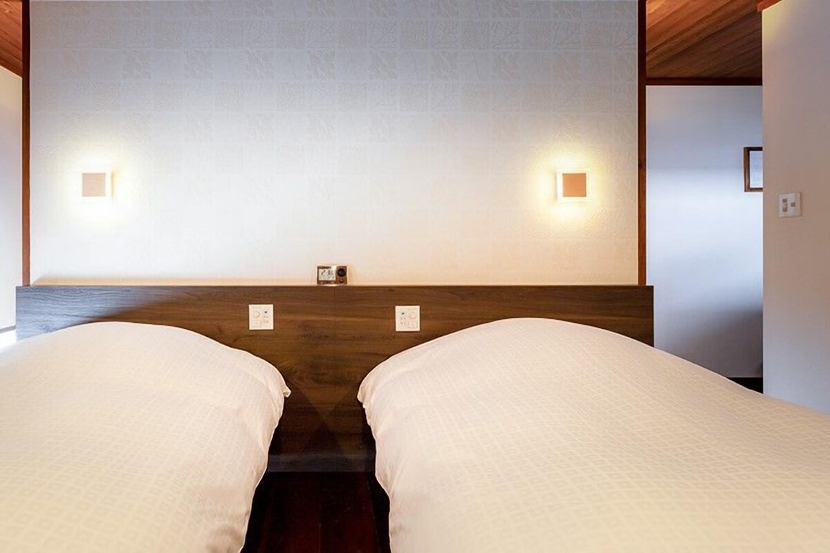 Una camera da letto con due letti, una testiera in legno e luci a parete.
