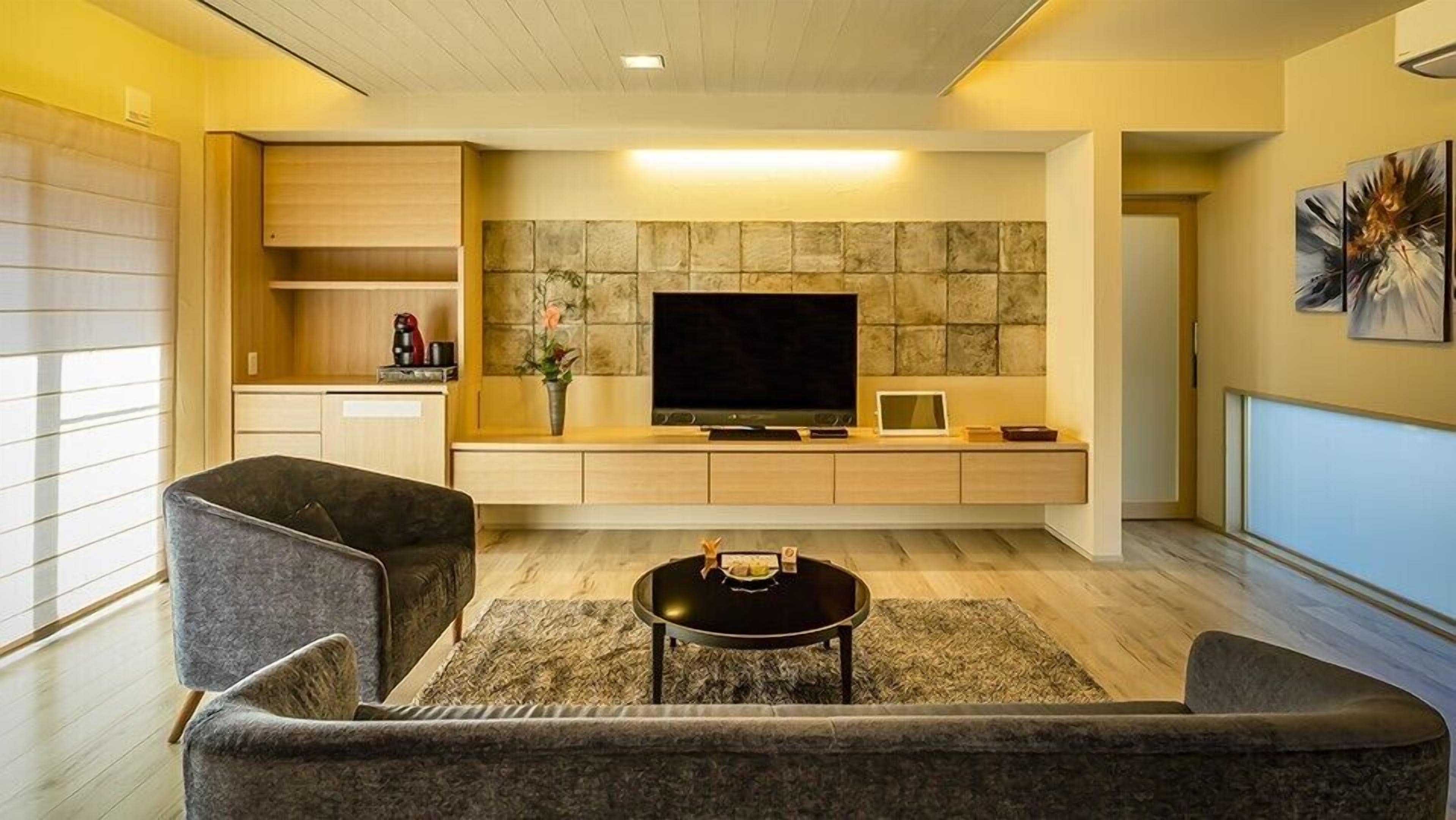 A modern living room with a sofa, a coffee table, a TV, and a stone wall.
