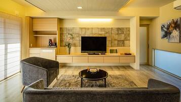 A modern living room with a sofa, a coffee table, a TV, and a stone wall.