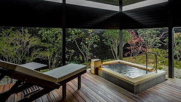A wooden deck with a hot tub and a bench.