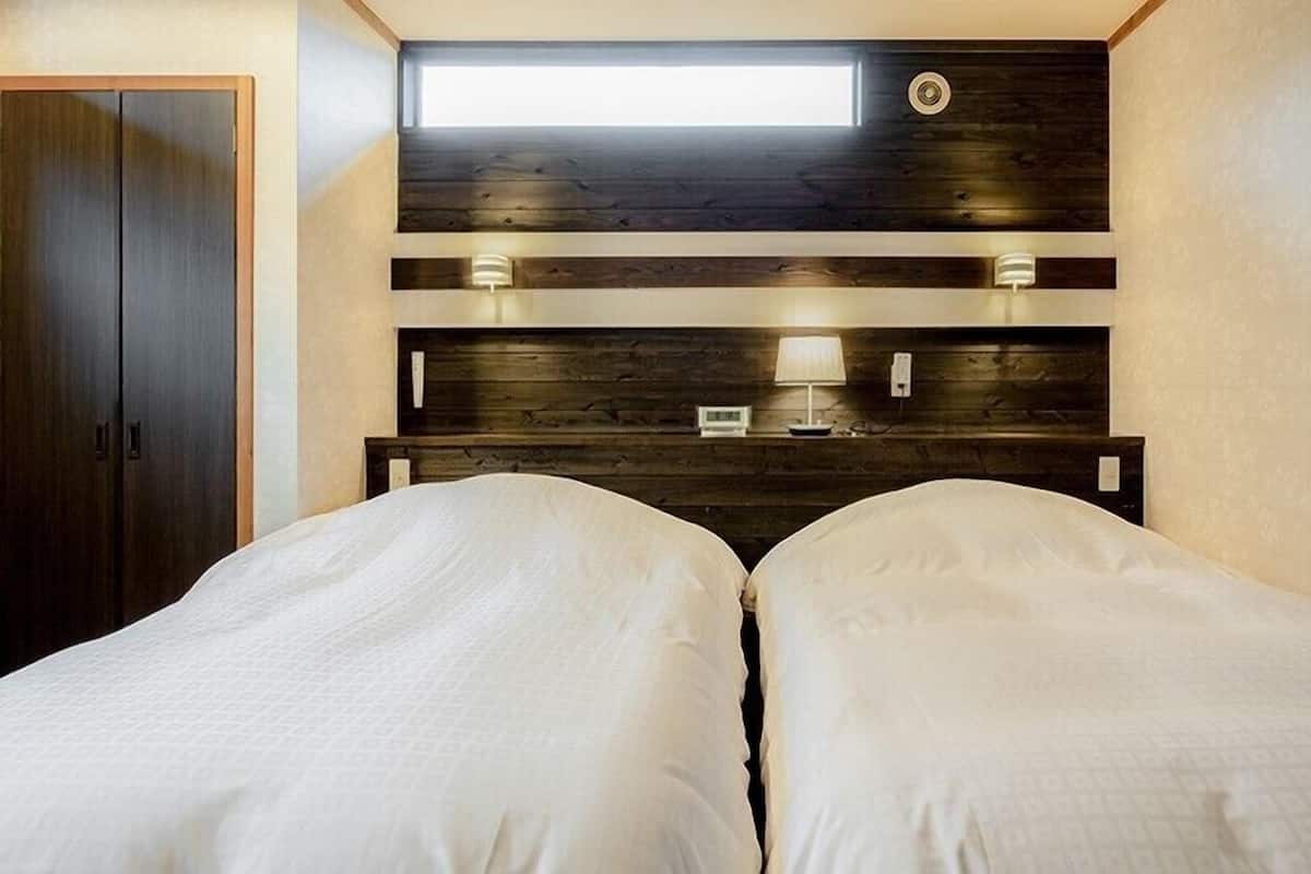 Quarto com duas camas, um claraboia, cabeceira de madeira e luminárias de cabeceira.