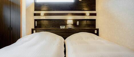 A bedroom with two beds, a skylight, a wooden headboard, and bedside lamps.
