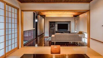 A traditional Japanese interior with tatami flooring, a low table, and a sofa.