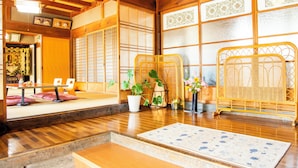 A traditional Japanese room with tatami flooring, a low table, cushions, a potted plant, and a woven screen. - Minshuku Yaichi (Gujo)