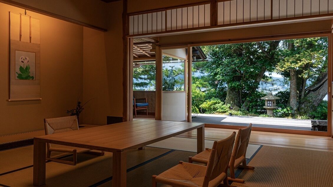 Ein traditioneller japanischer Raum mit Tatami-Bodenbelag, einem Holztisch und Stühlen.