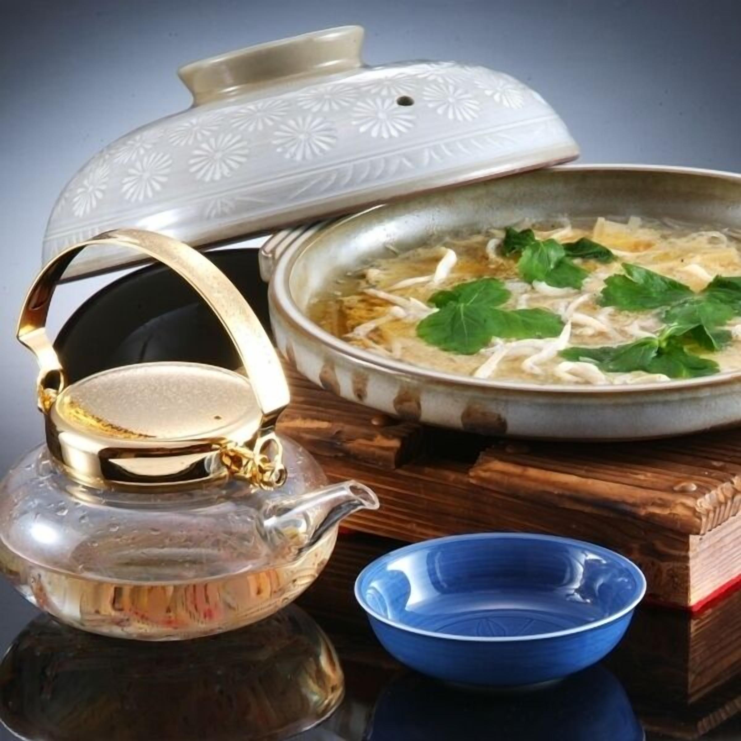 A teapot, a bowl, and a pot of soup on a wooden surface.