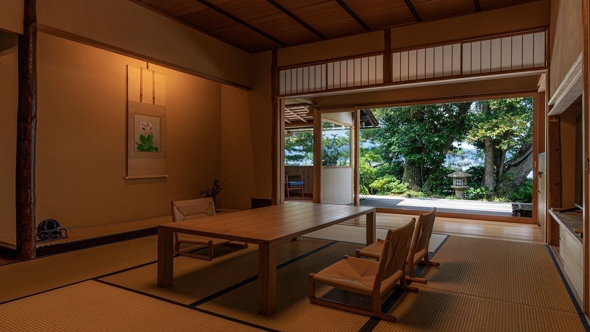 Ein traditioneller japanischer Raum mit Tatami-Boden, einem niedrigen Tisch und Stühlen.