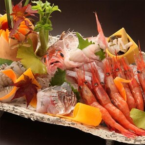 A seafood platter with various types of fish and shrimp, garnished with herbs and citrus slices. - Kamai Onsen Ippenan (Kyotango)