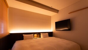 A hotel room with a large bed, a flat-screen TV mounted on the wall, and a ceiling light fixture. - Kamai Onsen Ippenan (Kyotango)