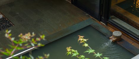 A water feature with a small waterfall, a stone basin, and a wooden platform.