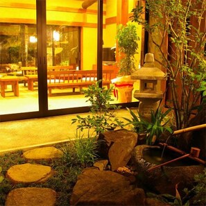 An indoor garden with a stone lantern, benches, and potted plants. - Kamai Onsen Ippenan (Kyotango)