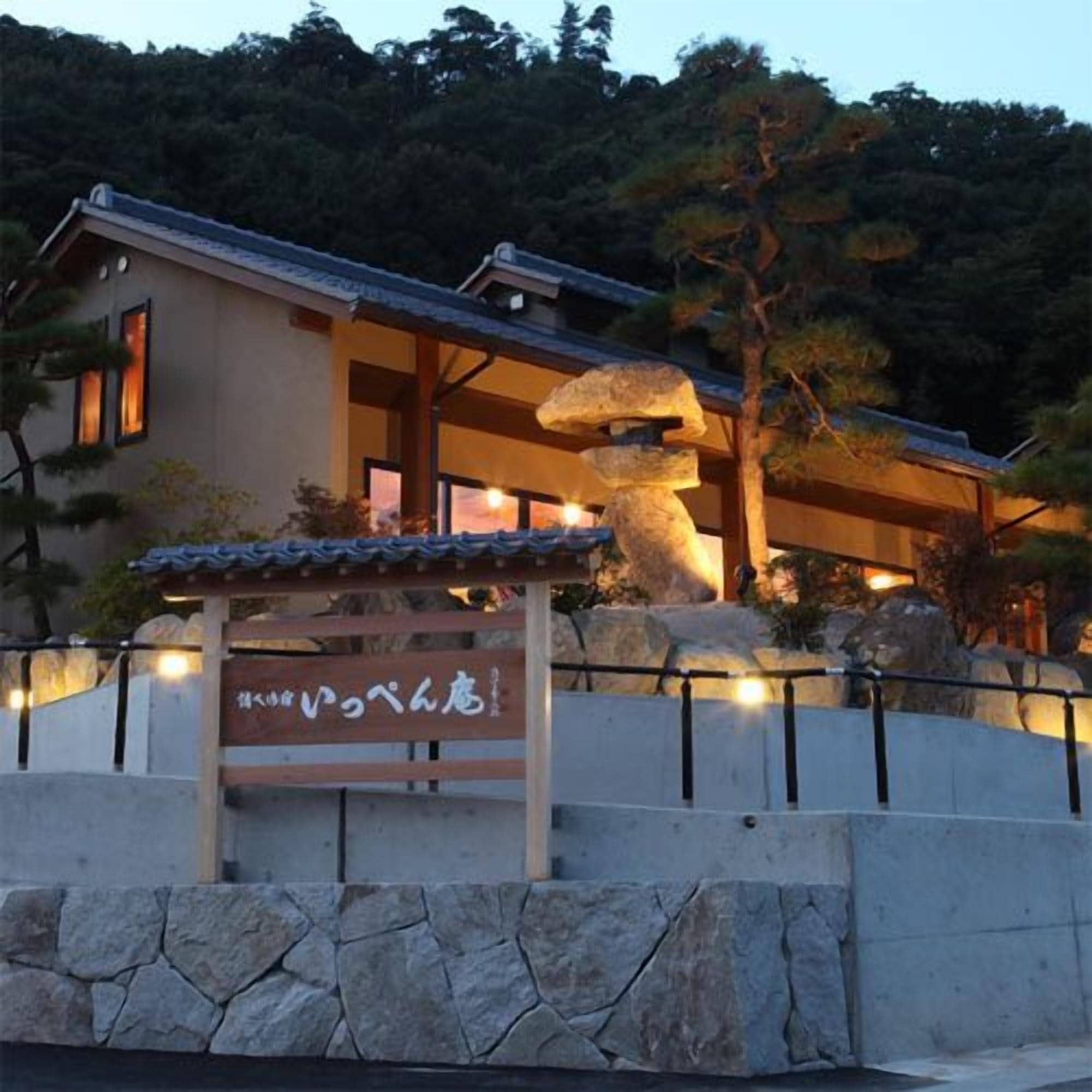 A traditional Japanese building with a stone lantern and a sign in front.