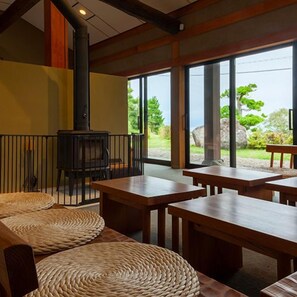 A room with a fireplace, wooden tables, and woven mats. - Kamai Onsen Ippenan (Kyotango)