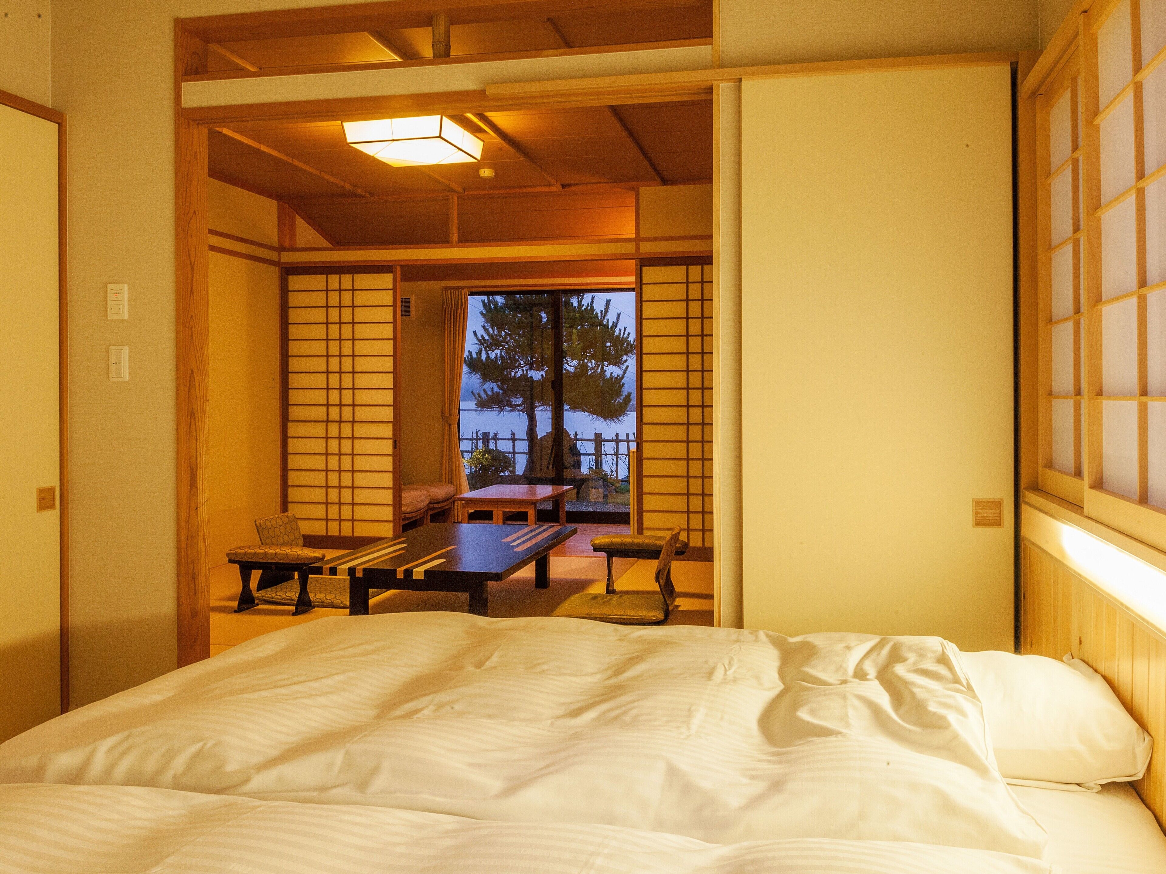 Una habitació japonesa tradicional amb tatami, una taula baixa, una banca i un llit.