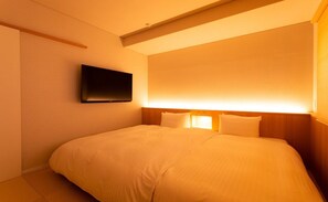 Habitación de hotel con cama, televisor de pantalla plana en la pared y lámpara de noche.