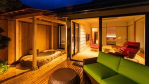 A modern outdoor relaxation area with a wooden deck, a hot tub, and a green sofa. - Kamai Onsen Ippenan (Kyotango)