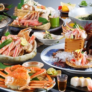 A variety of seafood dishes, including crab, sashimi, and sushi, arranged on a table. - Kamai Onsen Ippenan (Kyotango)