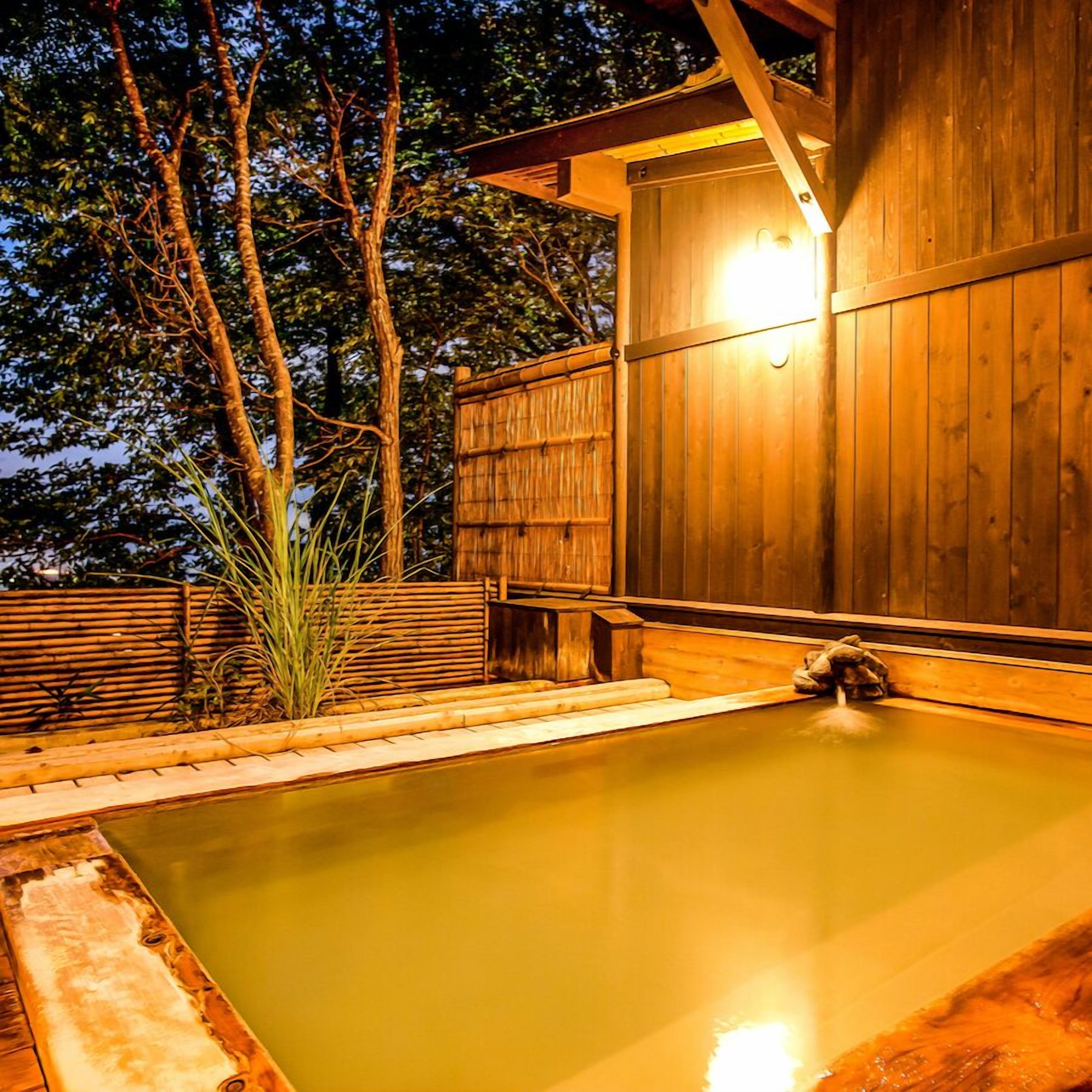Ein Holz-Spa mit Whirlpool, umgeben von Bambus und Bäumen.