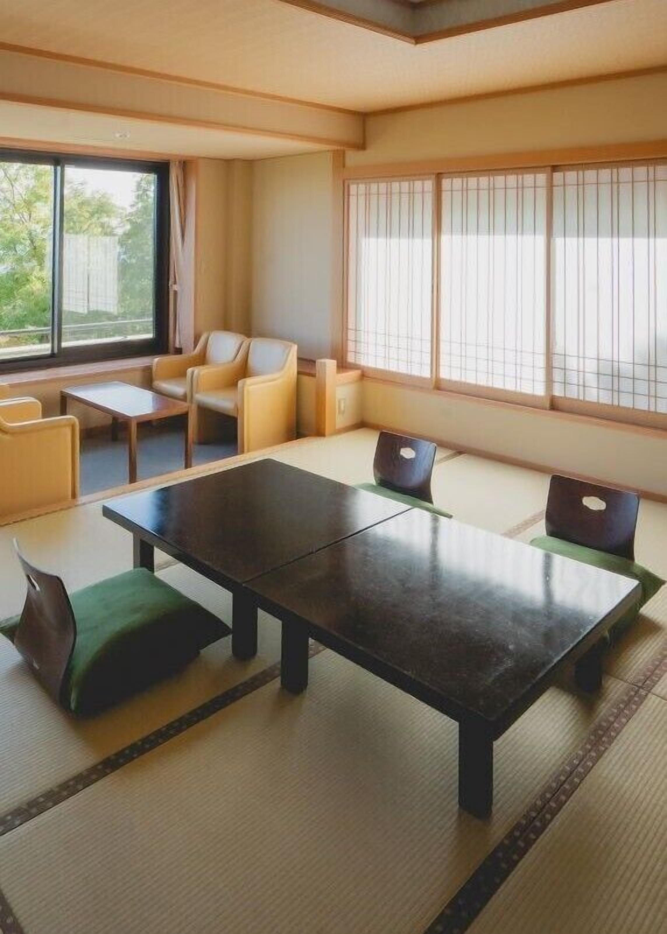 Una habitación japonesa tradicional con suelo de tatami, una mesa baja y asientos.