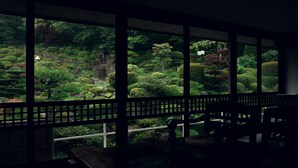 A room with large windows overlooking a meticulously landscaped garden with various trees and shrubs. - Dake Onsen Nagame no Yakata Kounkaku (Nihommatsu)