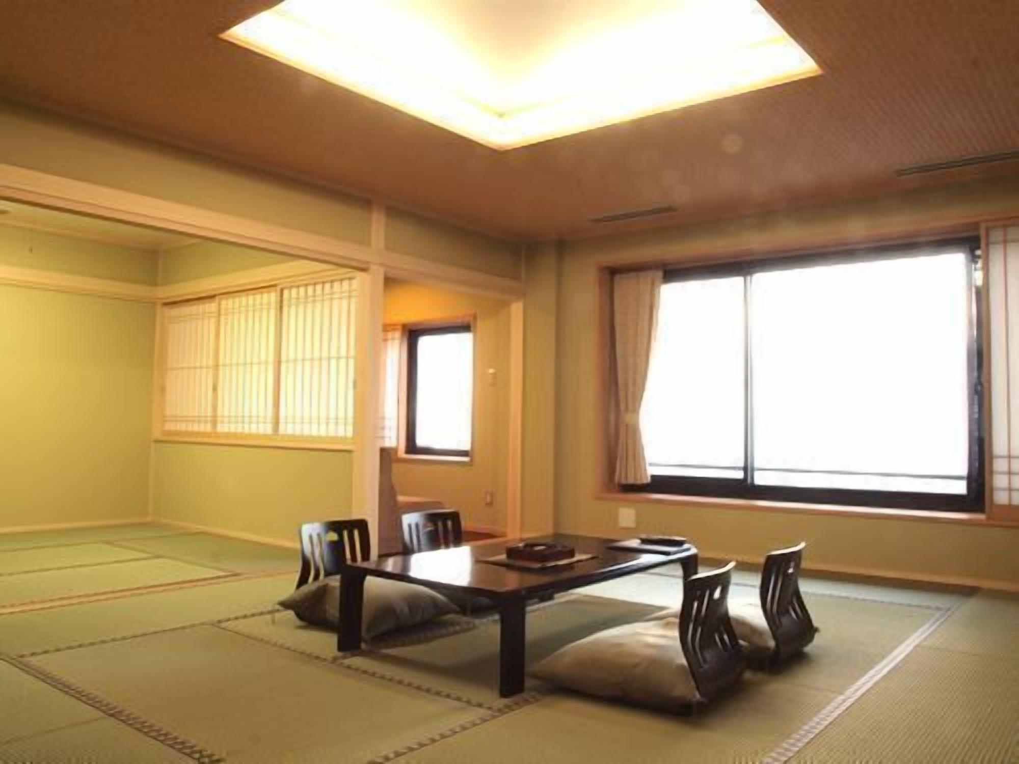 Una habitación japonesa tradicional con suelo de tatami, una mesa baja y puertas correderas.