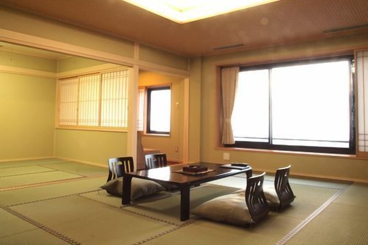 Une pièce de style japonais traditionnel, avec un sol recouvert de tatamis, une table basse et des portes coulissantes.