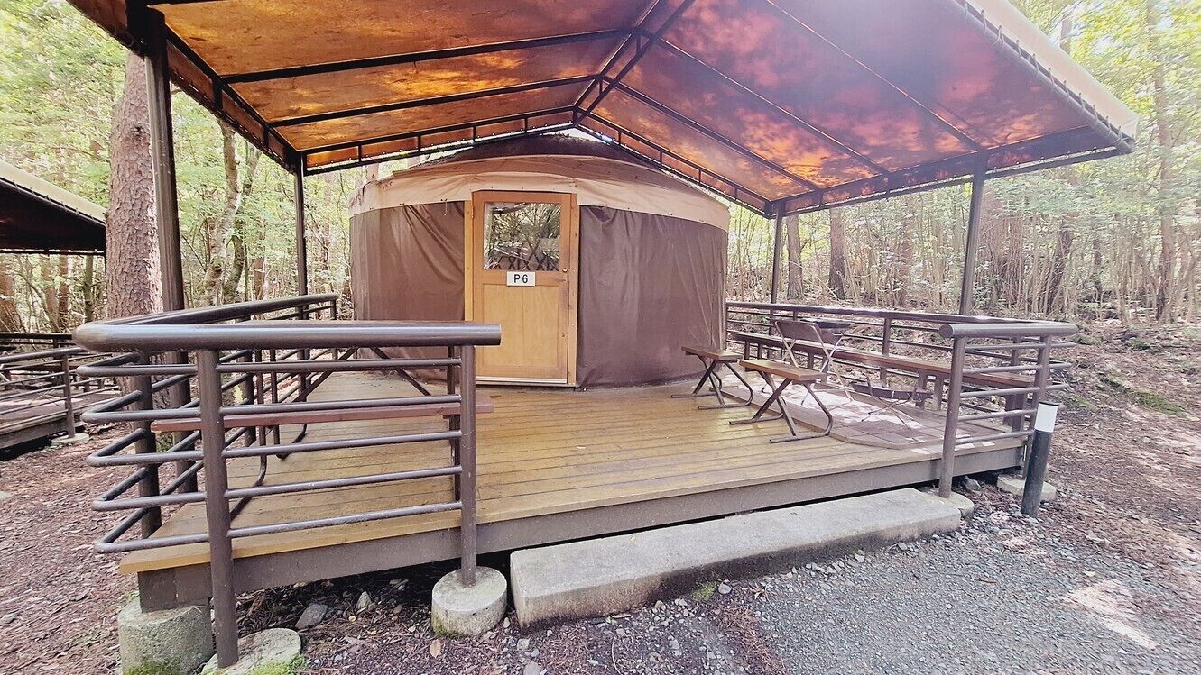 A circular wooden structure with a door labeled 'P6' and a covered wooden deck with benches.