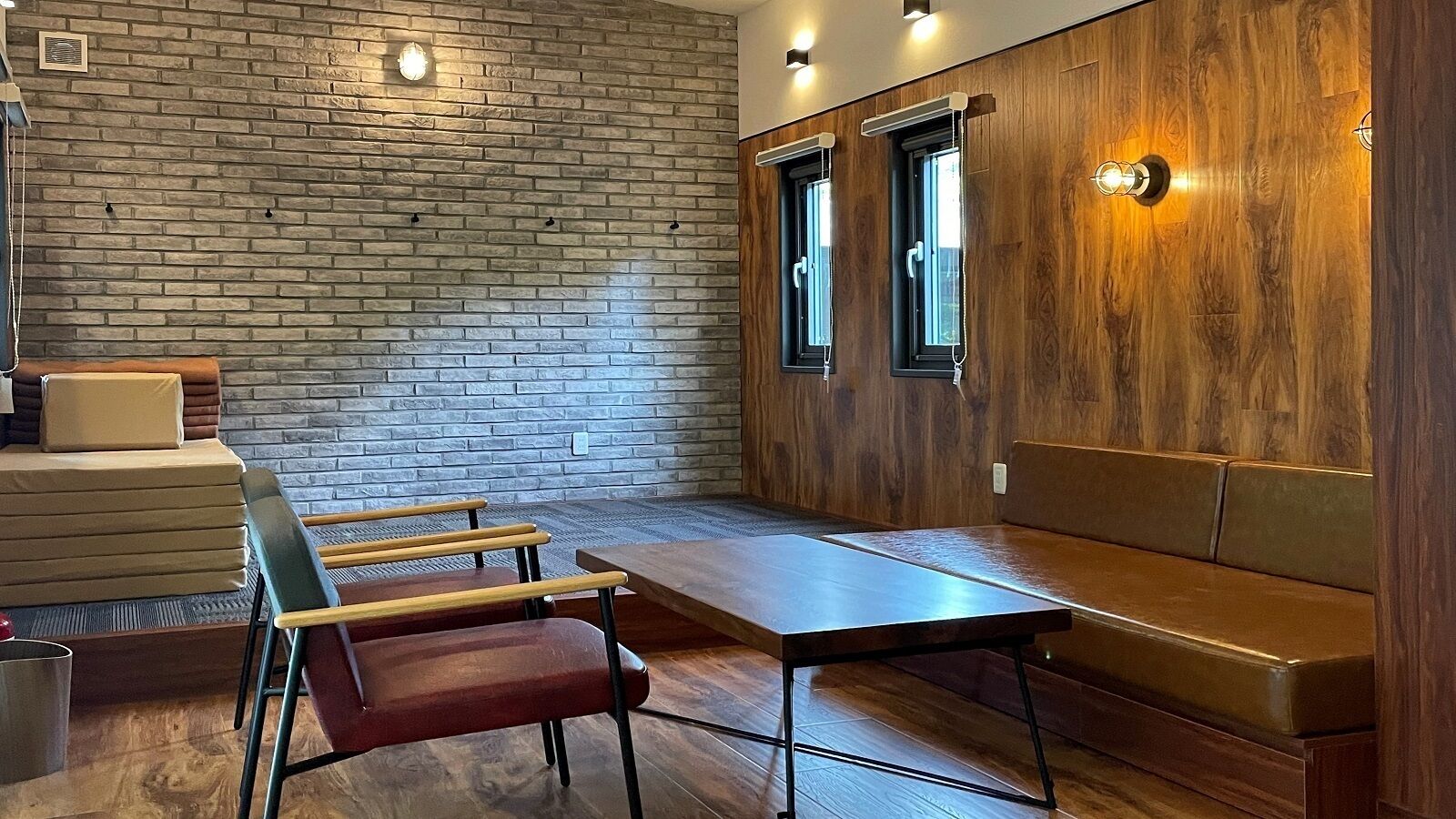 A room with a brick wall, wooden paneling, a bench, a table, and chairs.