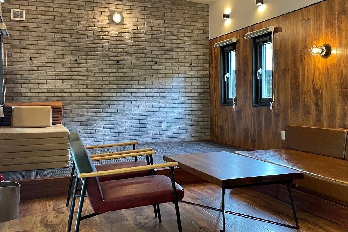 Une pièce avec un mur en briques, un lambris en bois, un banc, une table et des chaises.