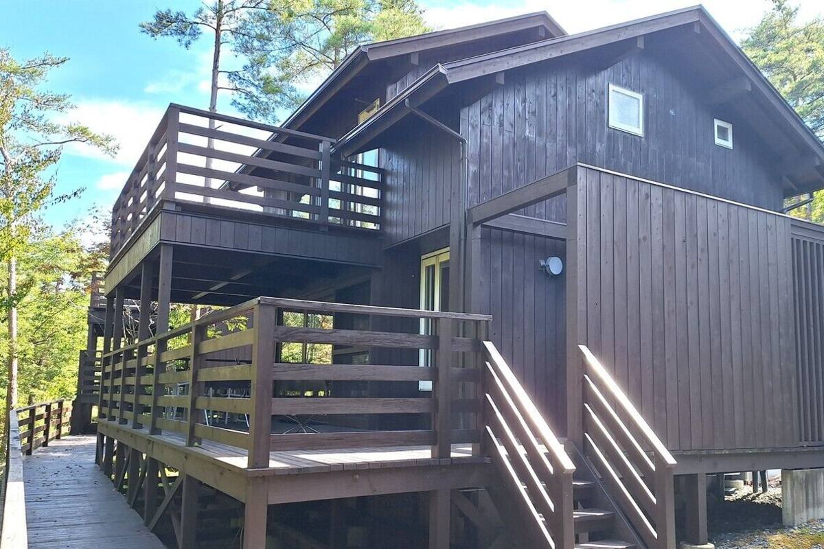 Une cabane dotée d’une terrasse en bois, d’un escalier et d’une grande fenêtre.
