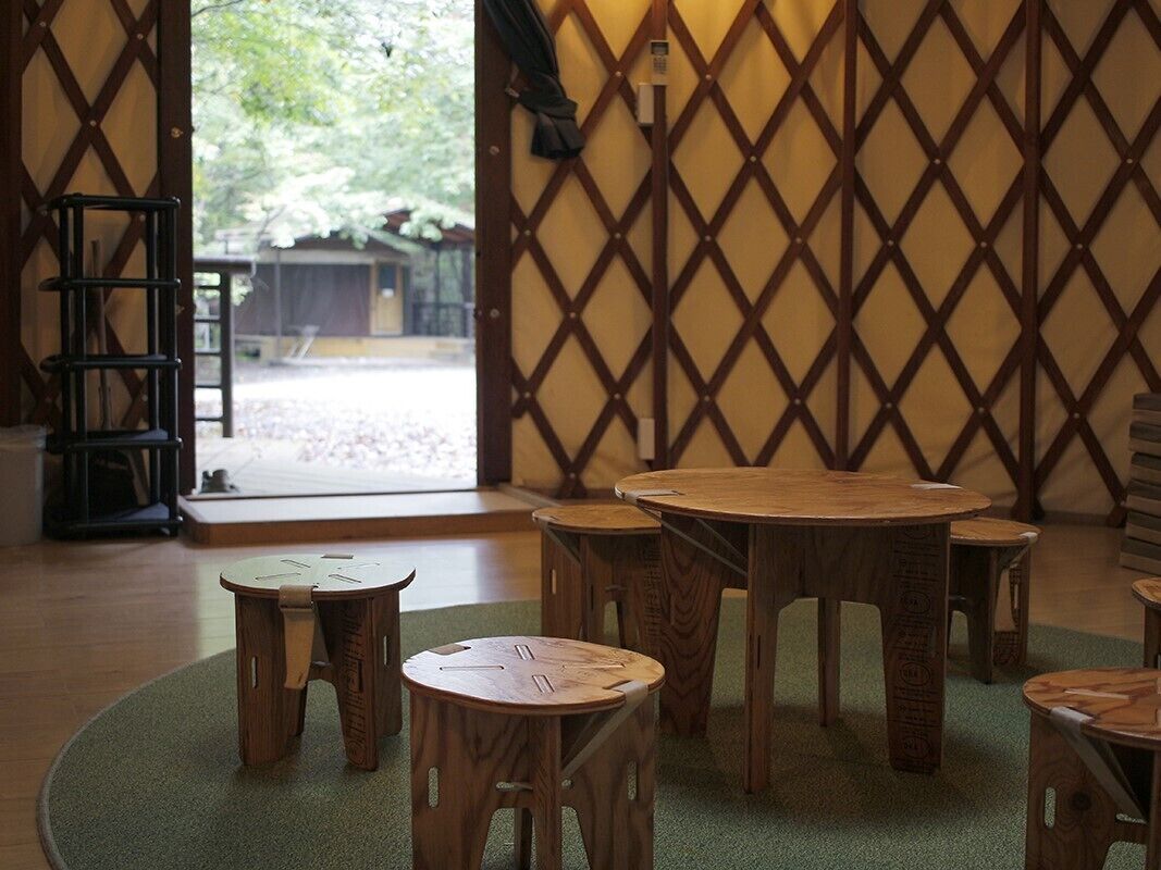 A room with a wooden lattice partition, a round table, and several stools.
