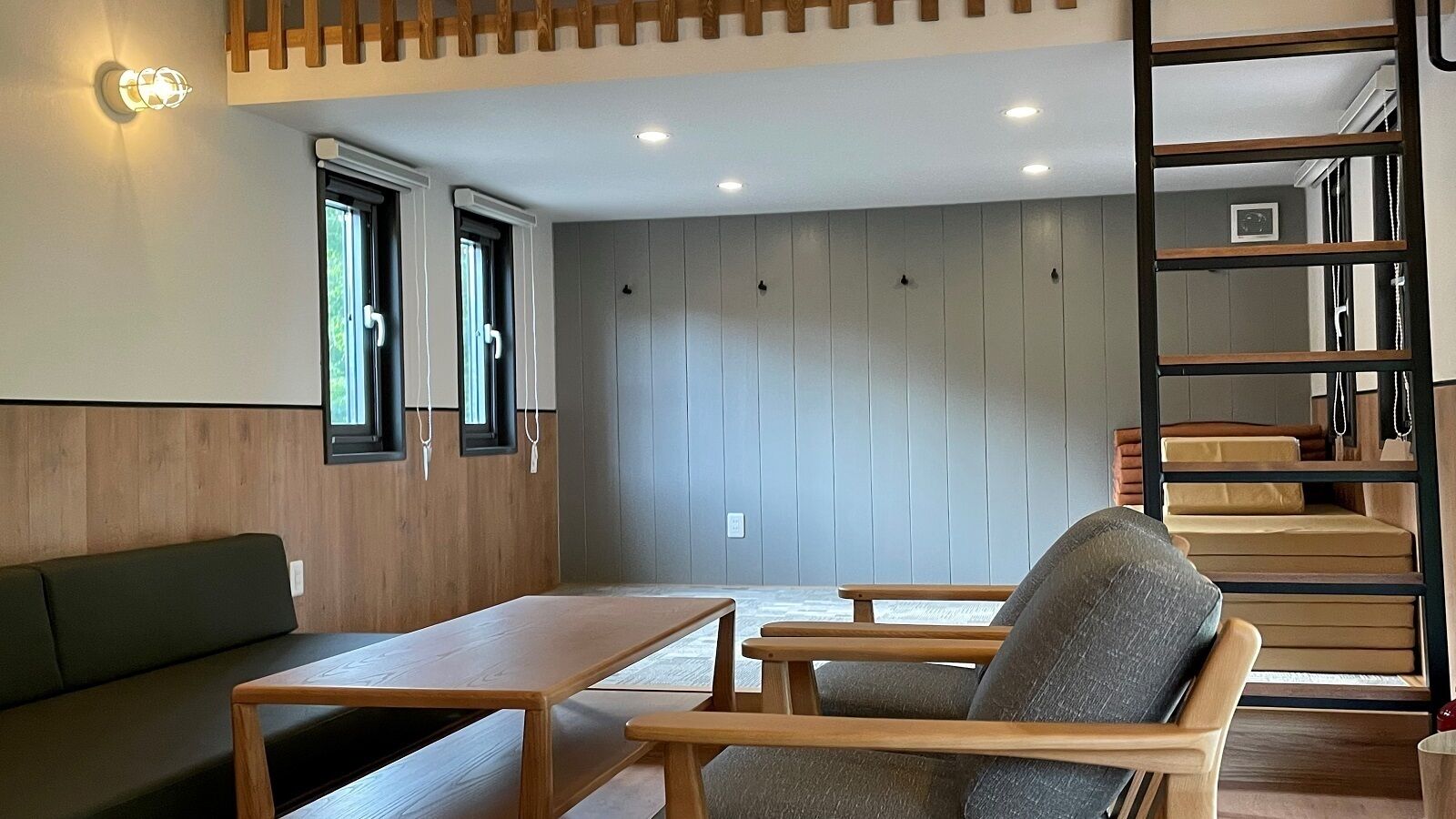 A room with a wooden bench, a table, a chair, a ladder, and a wall with vertical panels.