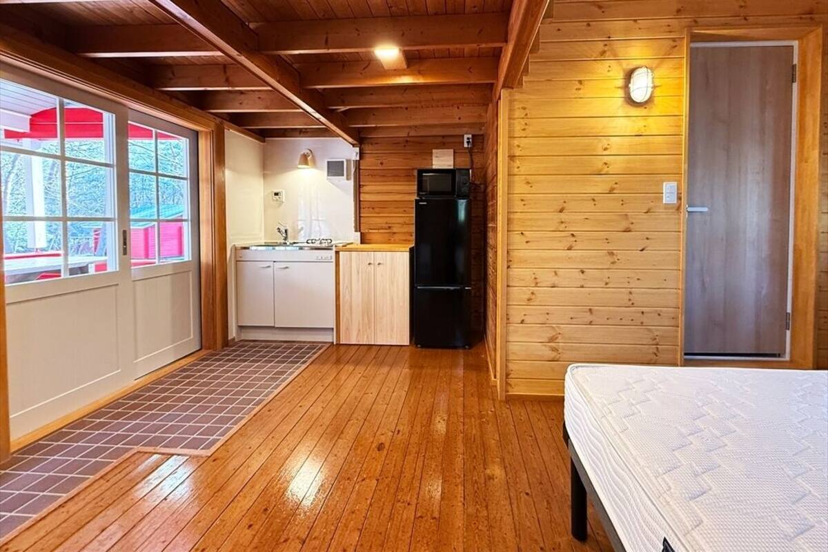 L’intérieur d’une cabane en bois, avec une cuisine, un lit et une porte.