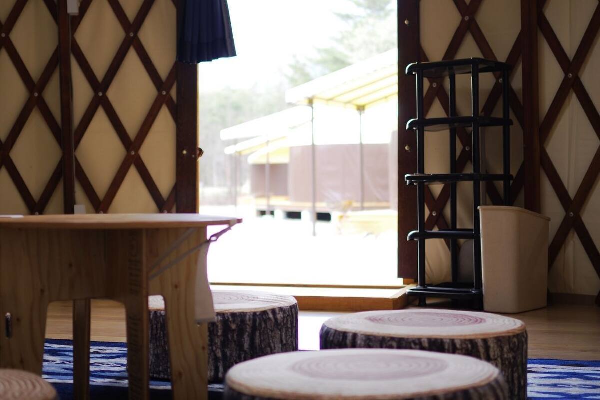 Une pièce avec une table en bois, des nattes rondes en tatami et une porte à treillis.