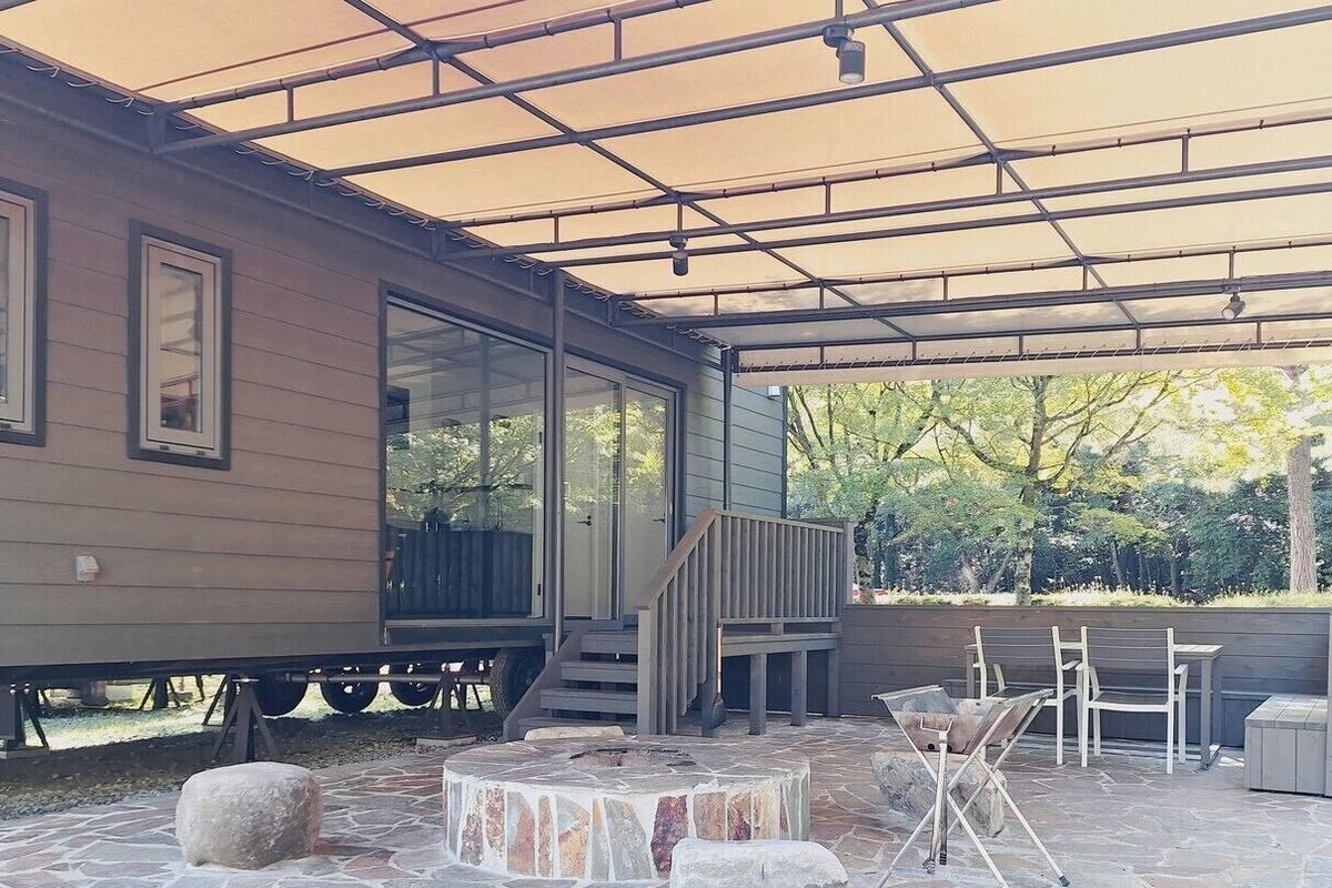 Un patio couvert avec un sol en pierre, une terrasse en bois et du mobilier d’extérieur.